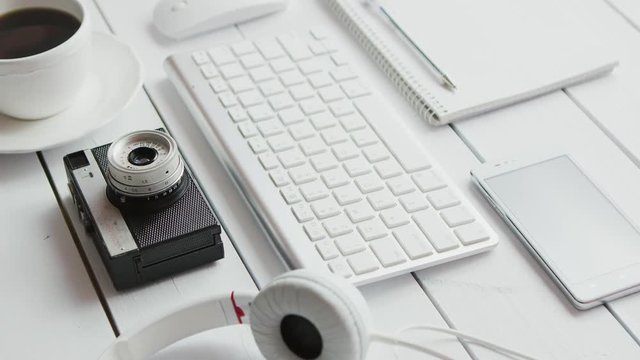 From above view of different office gadgets with photo camera laid near on white background