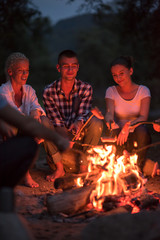 young friends relaxing around campfire