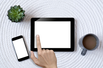 Close up of hand with long fingers holding tablet. Smartphone and notebook lie on table. Top view