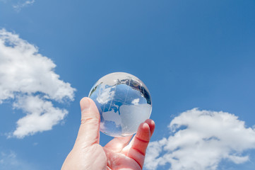 青空を背景にガラスの地球を掲げる手