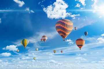 Foto op Canvas Kleurrijke heteluchtballonnen vliegen in blauwe lucht met witte wolken en felle sunshinr © IgorZh