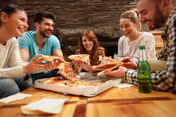 Group of young people eating's big pizza together