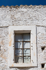 Fototapeta na wymiar Window and a white stone wall, Greece