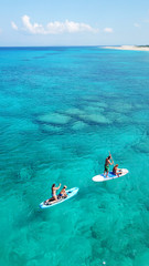 Aerial drone photo of couple practicing Stand Up Paddle or SUP in tropical exotic emerald and...