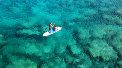 Aerial drone photo of couple practicing Stand Up Paddle or SUP in tropical exotic emerald and...