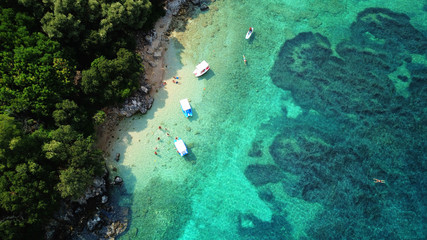 Aerial photo of iconic white cliff tropical bay forming a blue lagoon with deep turquoise clear ocean and docked small boats enjoying this unique paradise - obrazy, fototapety, plakaty