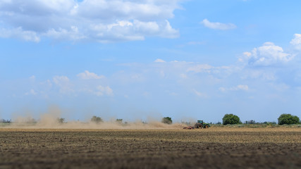 Obraz premium tractor plowing field on a hot summer day / agriculture field preparation for the following code
