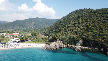 Aerial drone bird's eye view of popular beach of Karavostasi with beautiful clouds and turquoise sandy beach full of sunbeds at summertime, Epirus, Ionian, Greece