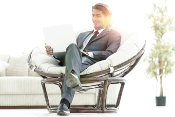 confident businessman working with laptop sitting in comfortable armchair