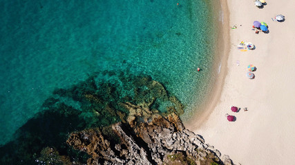 Aerial drone bird's eye view of popular beach of Karavostasi with beautiful clouds and turquoise sandy beach full of sunbeds at summertime, Epirus, Ionian, Greece