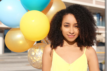 Fototapeta premium Beautiful African-American woman with balloons outdoors