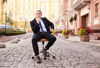 Thoughtful businessman sitting in office armchair outdoors