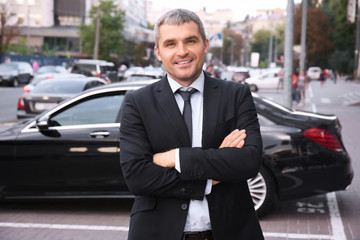 Handsome businessman with crossed arms outdoors