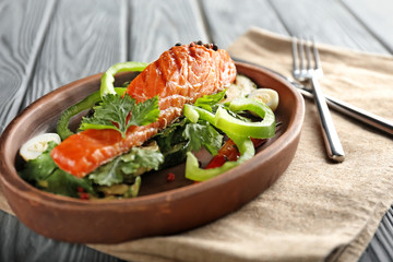 Plate with tasty salmon and fresh salad on wooden table
