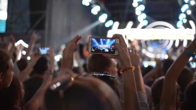 Hands Hold Mobile Camera With Digital Display Among People During Rock Concert