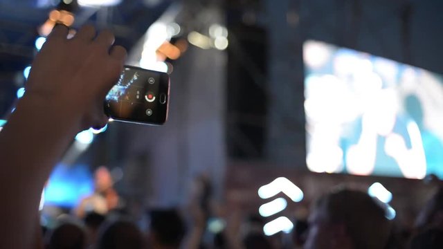 Hands Hold Mobile Camera With Digital Display Among People During Rock Concert