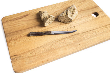 small loaf of whole wheat flour elongated next to a knife on a wooden board
