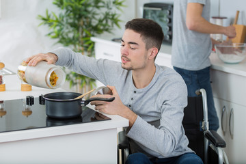 disabled young man in wheelchair cooking a meal in kitchen