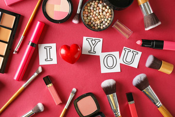Composition with decorative cosmetics and phrase I LOVE YOU on color background