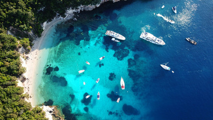 Aerial drone bird's eye view photo of sail boats in tropical caribbean paradise bay with white rock caves and turquoise clear sea
