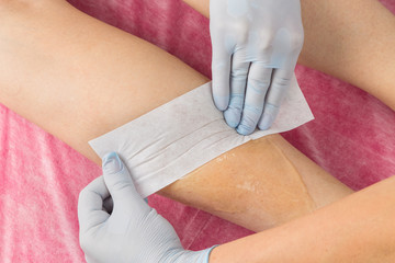 Removing unnecessary hair on the legs. Procedure sugaring in a beauty salon.Depilatory sugar paste