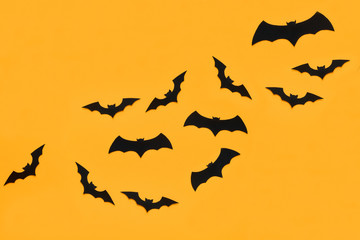 Halloween and decoration concept. Black paper bats flying over orange background. Halloween background.