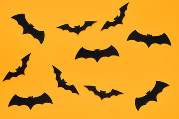 Halloween and decoration concept. Black paper bats flying over orange background. Halloween background.