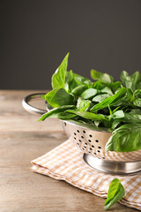 Colander with fresh green basil on wooden table