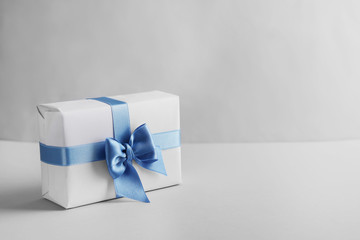 Gift box with blue ribbon on light background