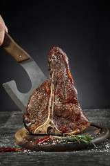 Grilled T-Bone Steak with salt and pepper on cutting board on dark background