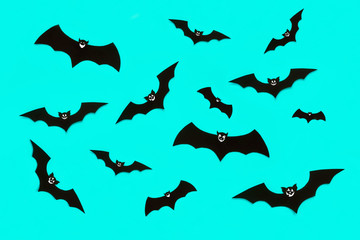 Halloween and decoration concept. Cute smiling black paper bats flying over pastel blue background. Halloween background.