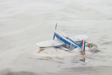 Fototapeta na wymiar Scale model hydroairplane on the surface of water. The plane begins to drown after an unsuccessful landing. Copy space. Toy