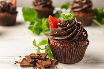 Tasty chocolate cupcakes on white wooden table