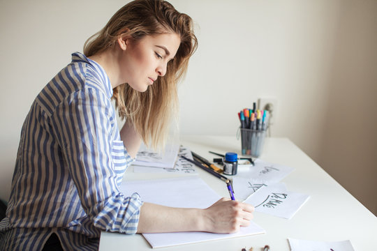 Portrait of young woman writing on paper on desk