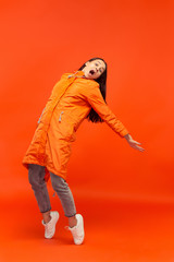 The young girl posing at studio in autumn jacket isolated on red. Human negative emotions. Concept of the cold weather. Female fashion concepts