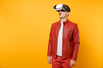 Portrait vogue handsome young man in red leather jacket, t-shirt looking in headset standing isolated on bright trending yellow background. People sincere emotions lifestyle concept. Advertising area.