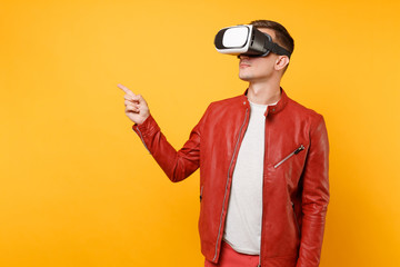 Portrait vogue cute young man in red leather jacket t-shirt looking up in headset standing isolated on bright trending yellow background. People sincere emotions lifestyle concept. Advertising area.