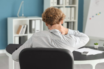 Businessman suffering from neck pain in office
