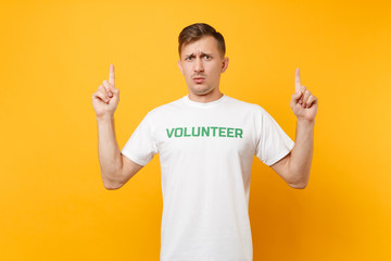 Portrait of displeased irritated young man in white t-shirt with written inscription green title...