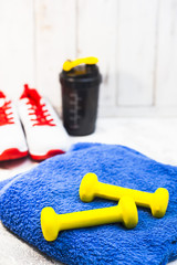 Time for diet slimming weight loss concept. Sport fitness, apple, sneakers, bottle of water and yellow weights on white wooden background. Vintage retro instagram filter