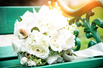 The blurry light design background of white rose bouquet put on green chair,warm light tone,