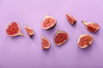 Cut ripe figs on color background