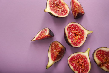 Cut ripe figs on color background