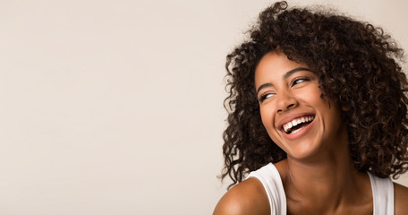 Fototapeta premium Śmiejąc się Afro-kobieta, patrząc od hotelu na jasnym tle
