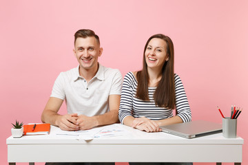 Two young smiling business woman man colleagues sit work at white desk with contemporary laptop...