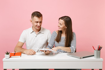 Two young smiling business woman man colleagues sit work at white desk with paper documents...