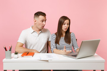 Two young smiling business woman man colleagues sit work at white desk with contemporary laptop...