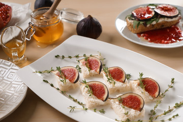 Tasty canapes with ripe fig and cream cheese on plate
