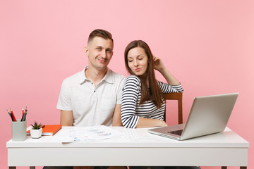 Two young tender business woman man colleagues sit work at white desk with contemporary laptop...