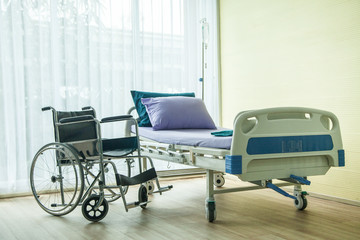 wheelchair and bed in the hospital waiting used for sick people. the bed near window have light from sun shine
